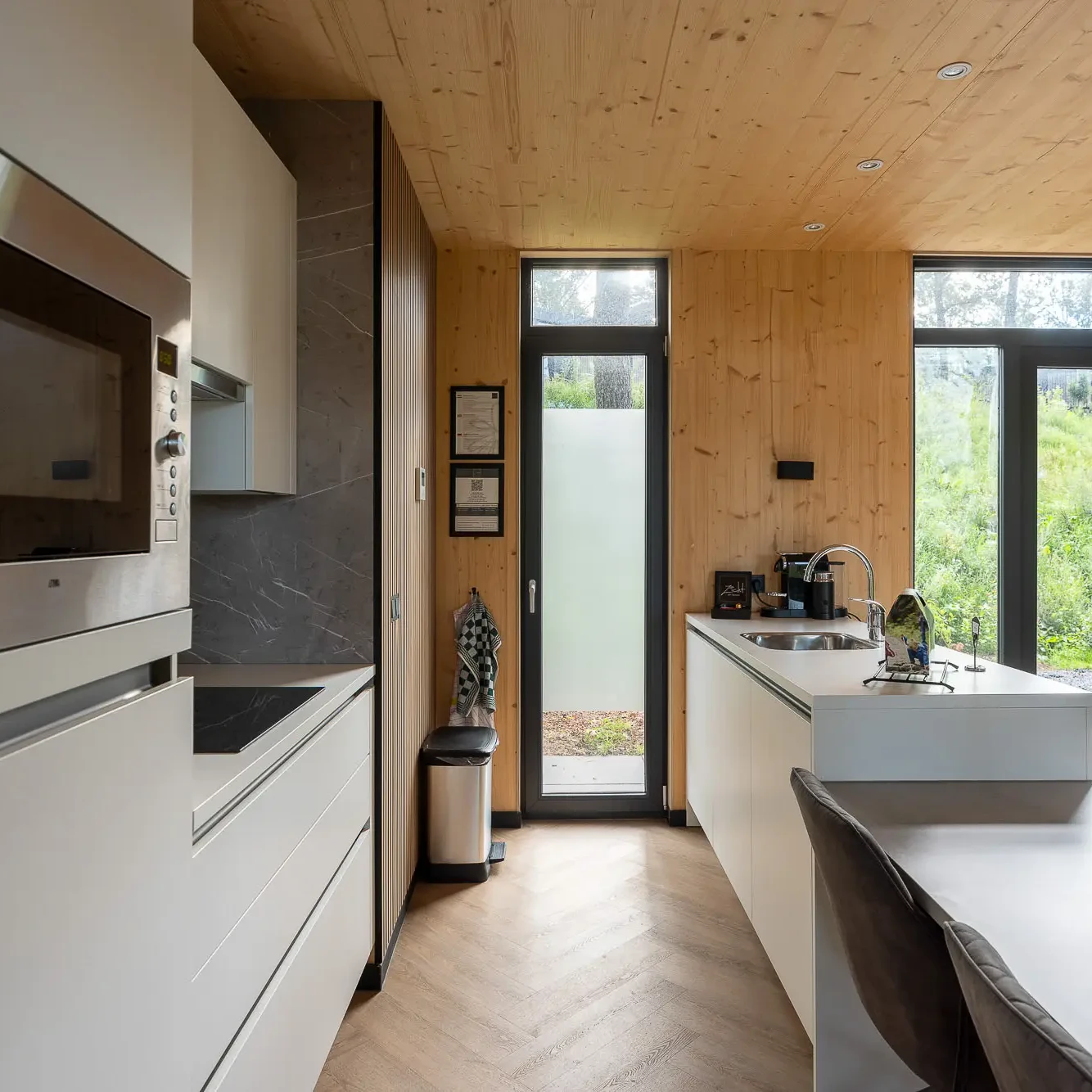 Moderne keuken in Panorama lodge met houten plafond, witte kasten en uitzicht op natuur in Markelo