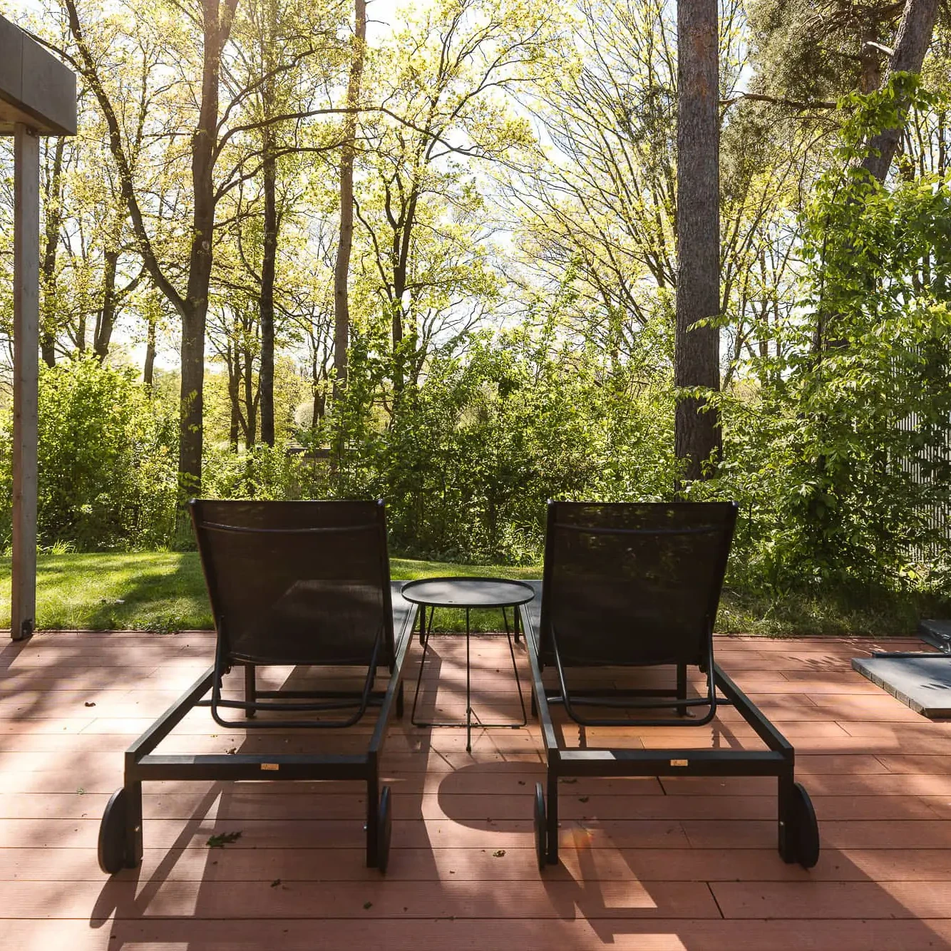 Twee ligbedden op houten terras met uitzicht op groene bossen bij Zicht op Twente Lodges