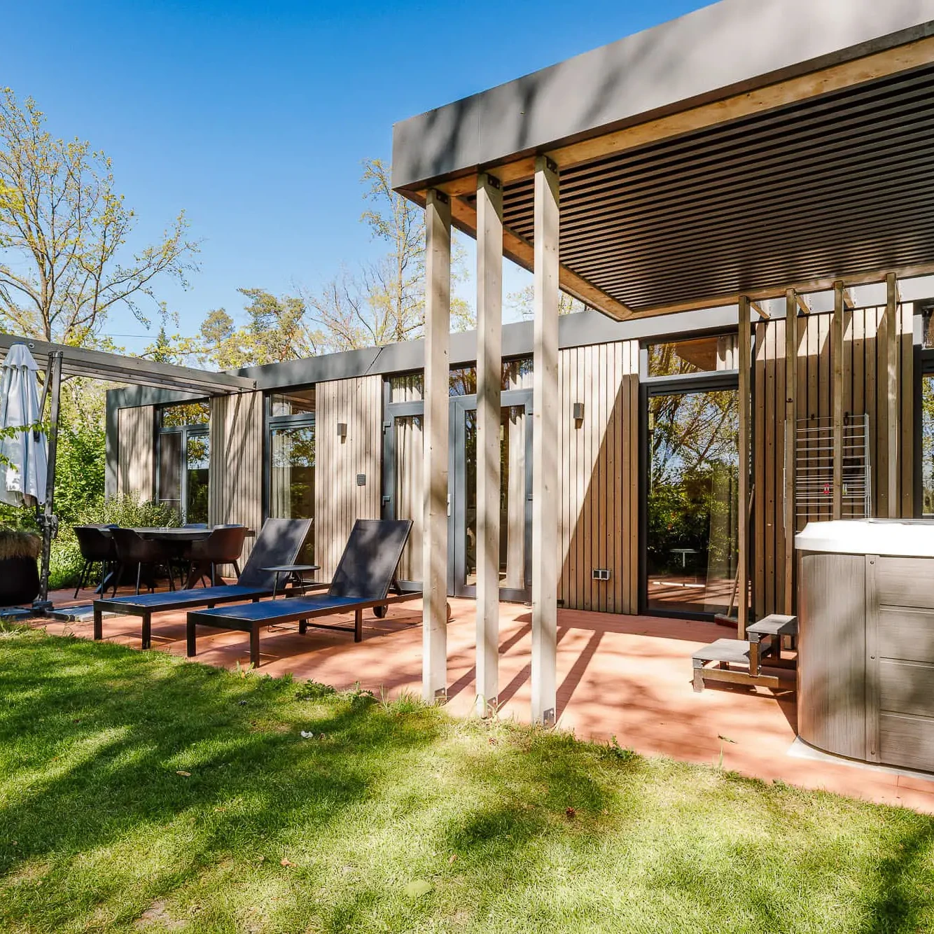 Luxe lodge met terras, ligbedden en jacuzzi omgeven door natuur in Markelo