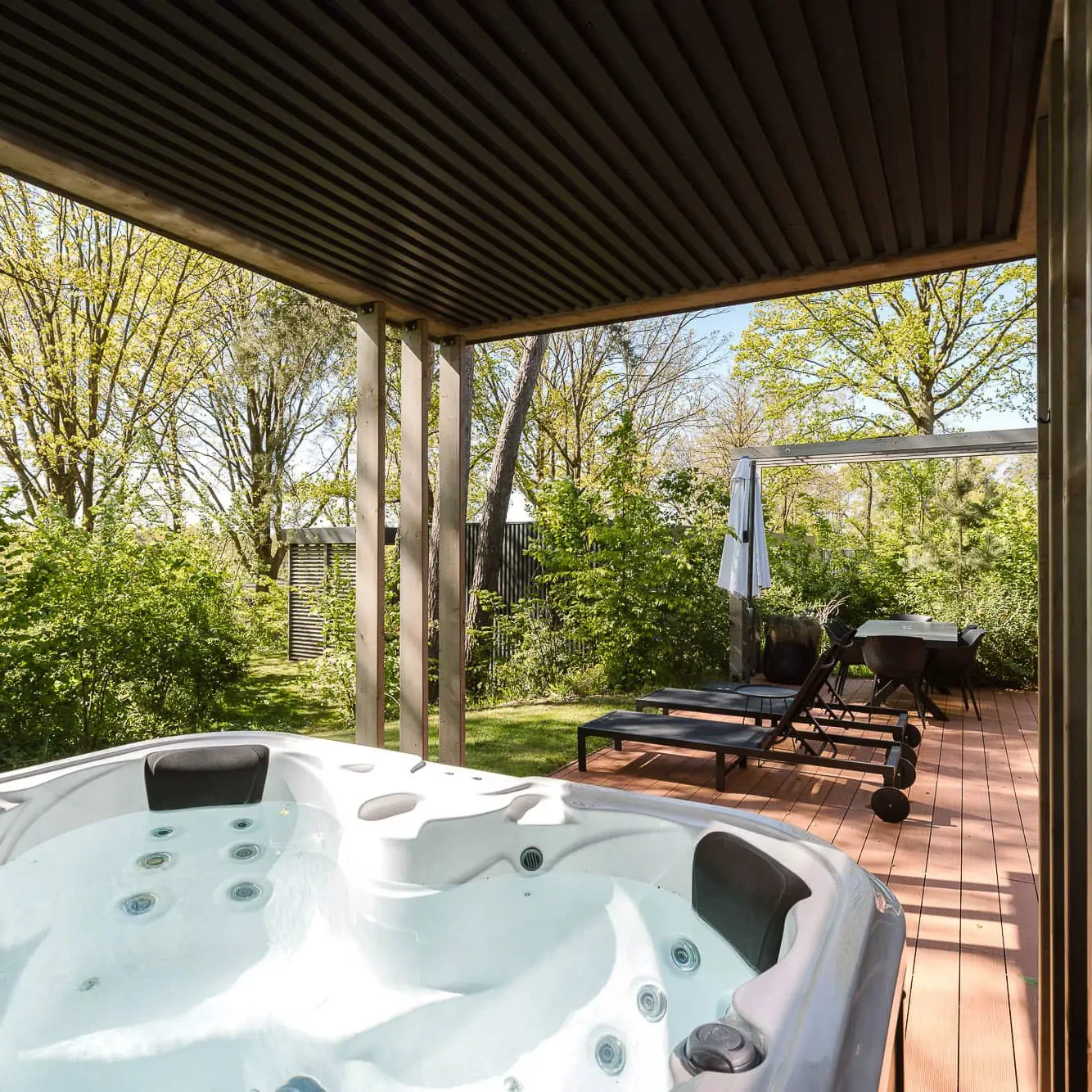 Privé jacuzzi op houten terras met uitzicht op groene natuur bij Zicht op Twente lodge