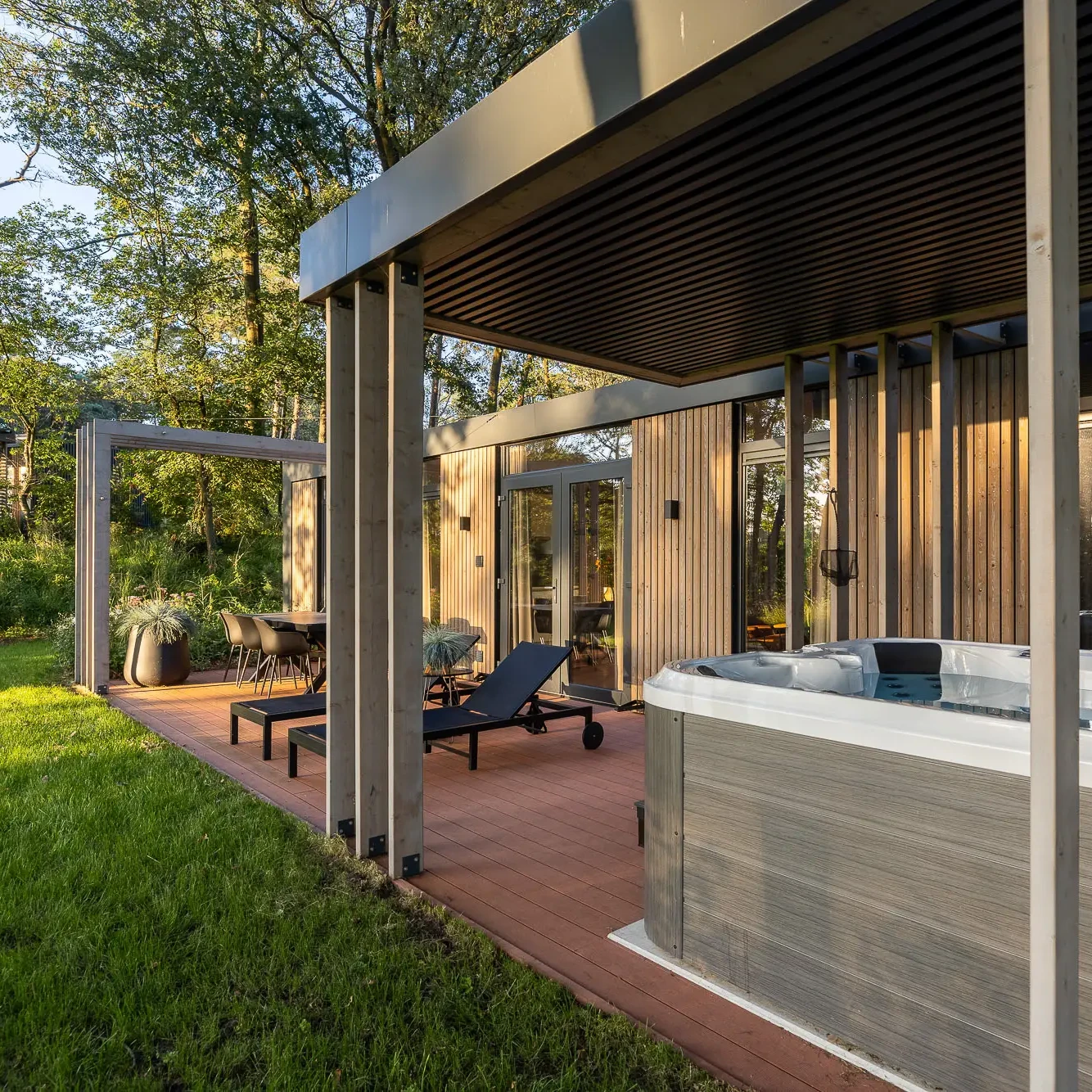 Luxe panorama lodge met privé jacuzzi en ligbedden op houten terras in bosrijke omgeving Markelo