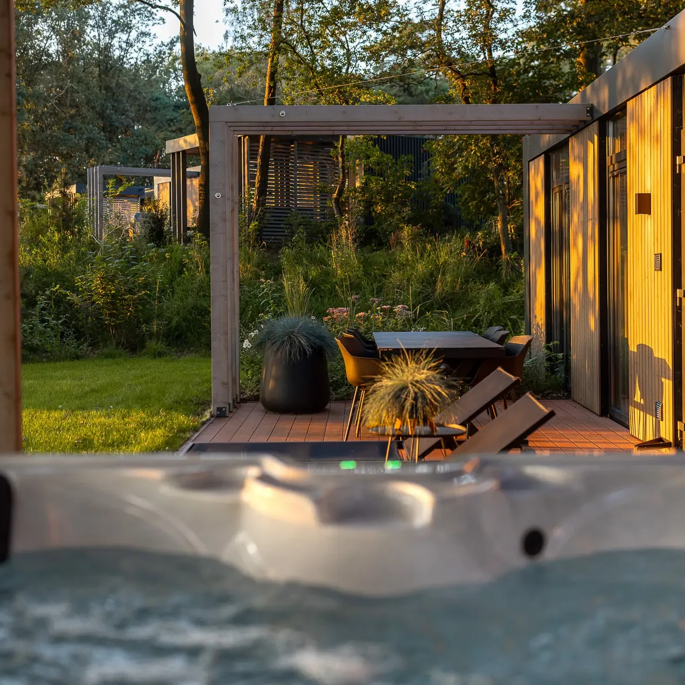 Buitenjacuzzi met uitzicht op terras en groene tuin bij luxe lodge in Markelo