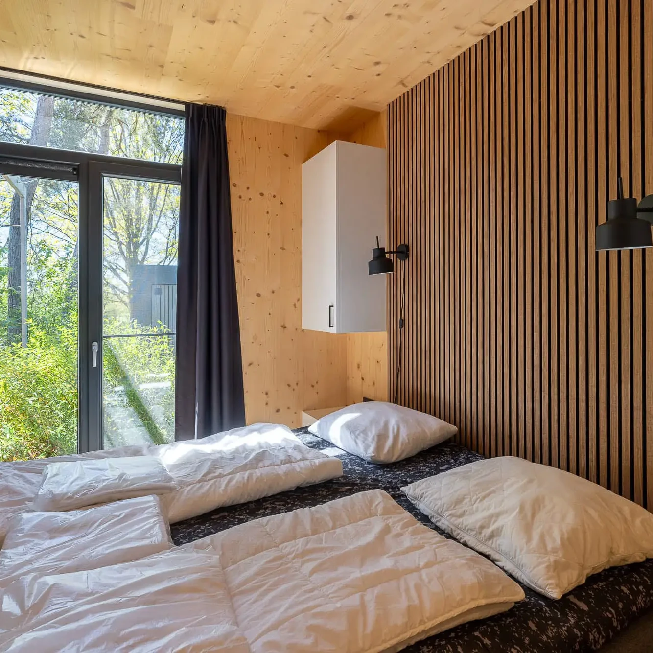 Moderne slaapkamer met houten wanden en plafond in Panorama Lodge Markelo met uitzicht op natuur