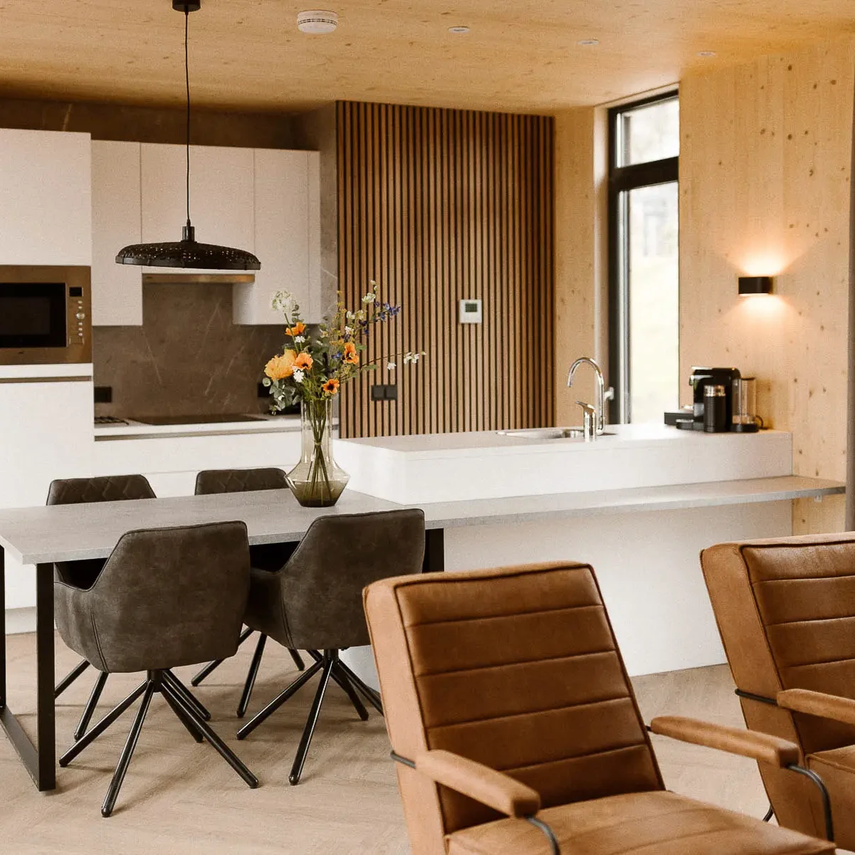 Moderne woonkamer met eethoek en open keuken in luxe Panorama lodge Markelo