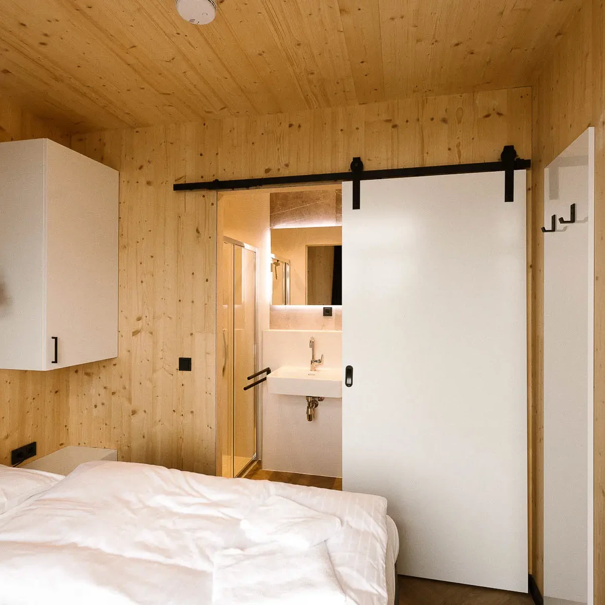 Luxe slaapkamer met houten wanden en plafond, ensuite badkamer met schuifdeur in Panorama Lodge Markelo