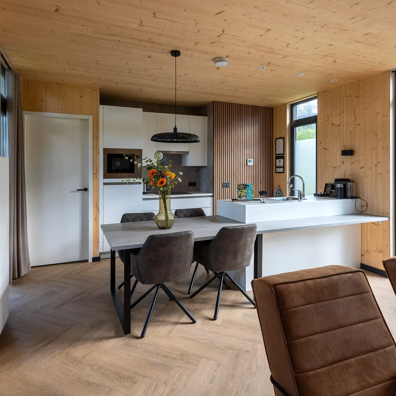 Moderne open keuken en eetkamer met houten interieur in luxe Panorama lodge Markelo