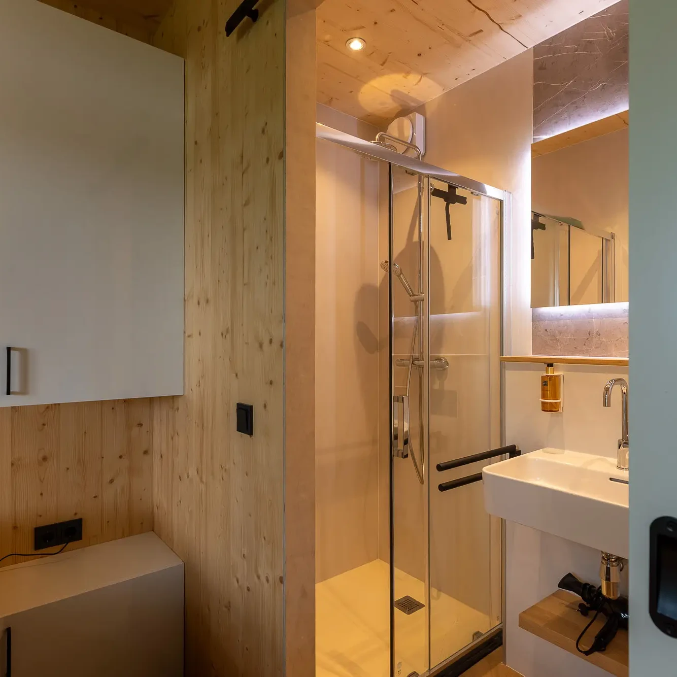 Compacte badkamer met glazen douchecabine en houten wandafwerking in Panorama Lodge Markelo